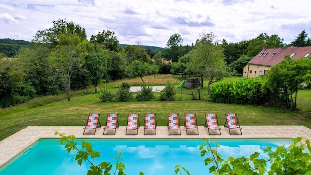 Una piscina con lettini e una casa sullo sfondo.