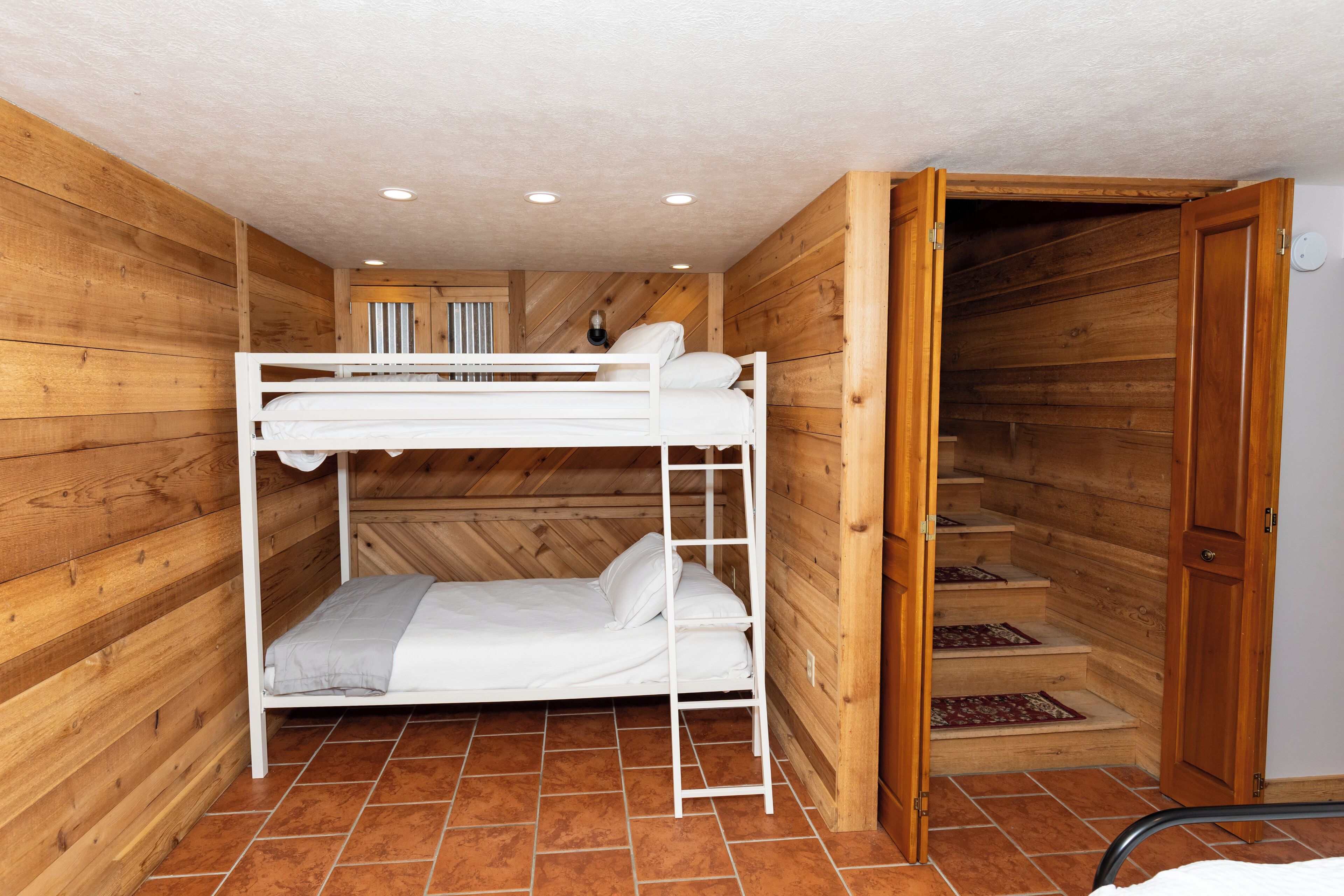 A bunk bed room with wooden walls and a tiled floor.
