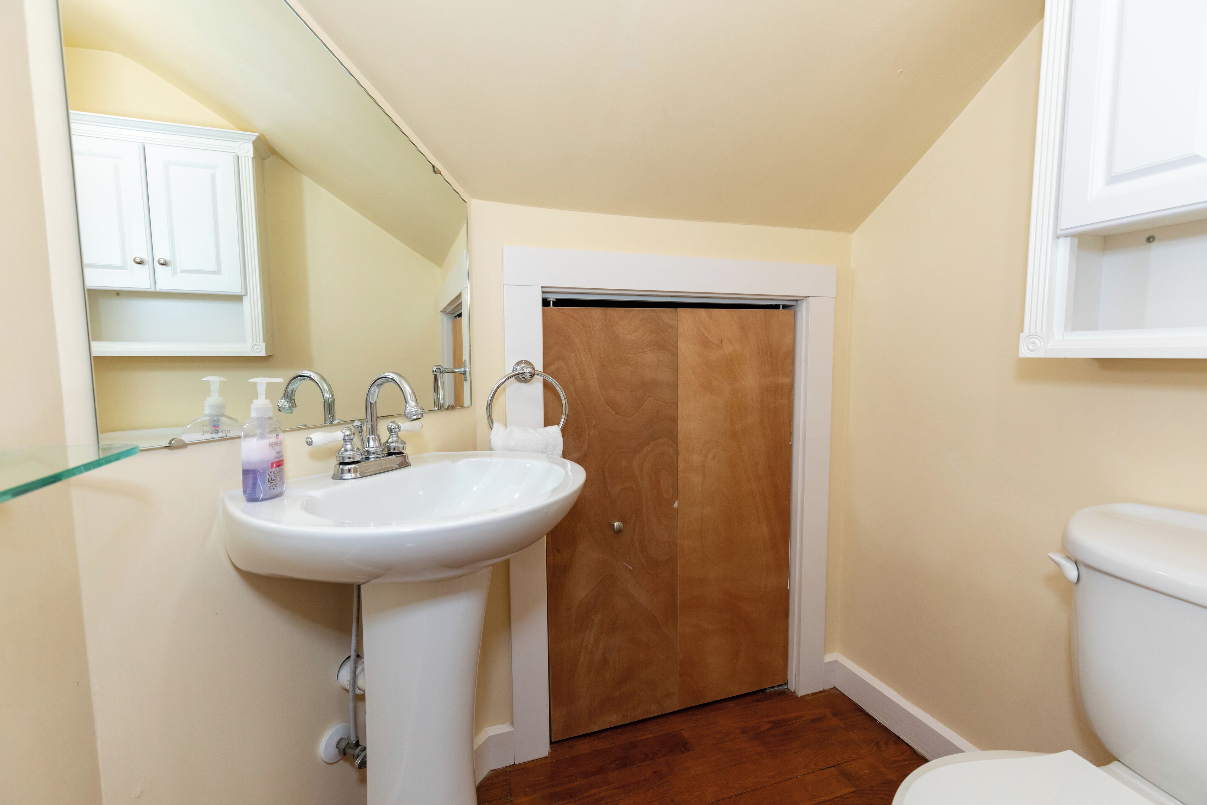 A bathroom with a white sink, wooden door, and a toilet.