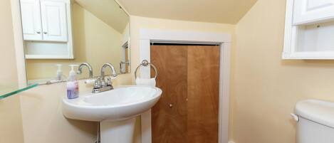 A bathroom with a white sink, wooden door, and a toilet.