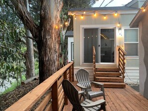 An outdoor deck with wooden railings, a wooden staircase, and two Adirondack chairs. - Peaceful tiny home with two queens and a loft (San Luis Obispo)