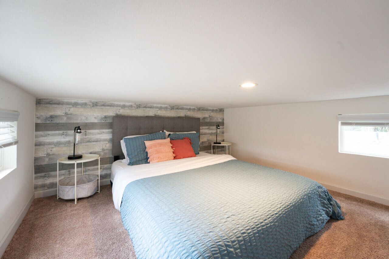 A bedroom with a bed, a nightstand, a lamp, and a window.