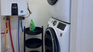 A laundry room with a front-loading washing machine, a dryer, and a water heater. - Updated Bungalow - Close to town and 30 min from Lubbock! (Brownfield)