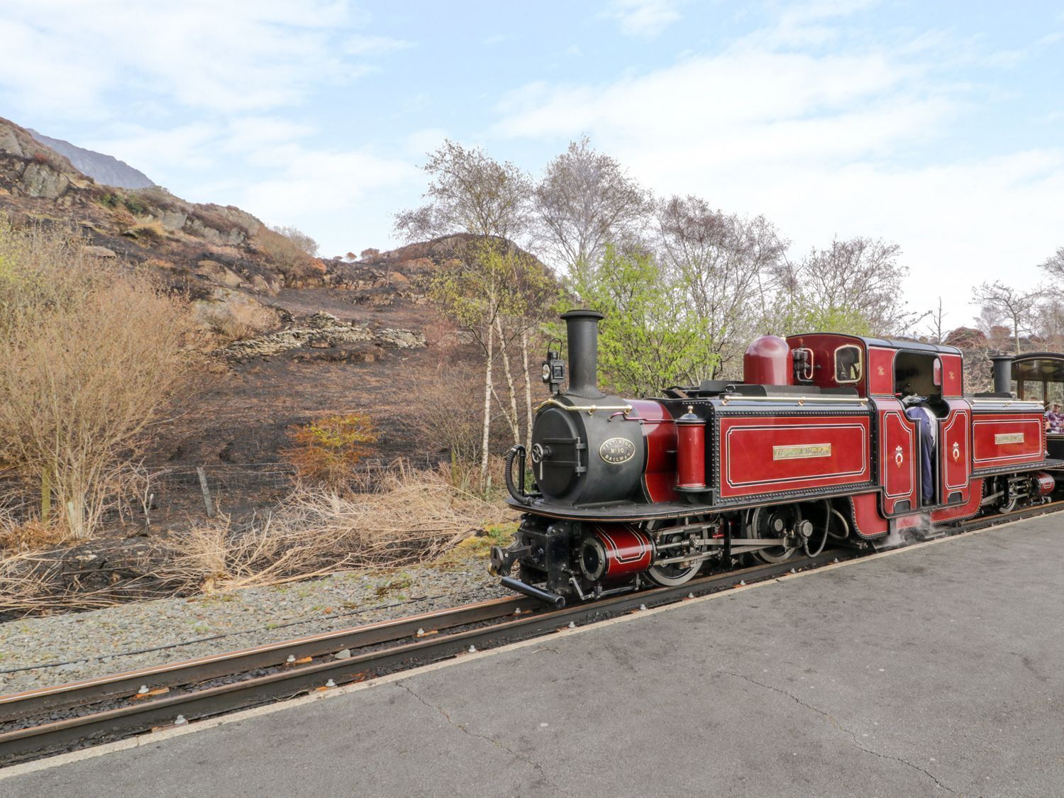 A vintage steam locomotive on a railway track with a mountainous backdrop.