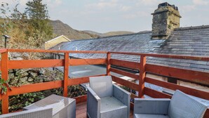 Eine Holzterrasse mit Korbmöbeln und einer Steinmauer.