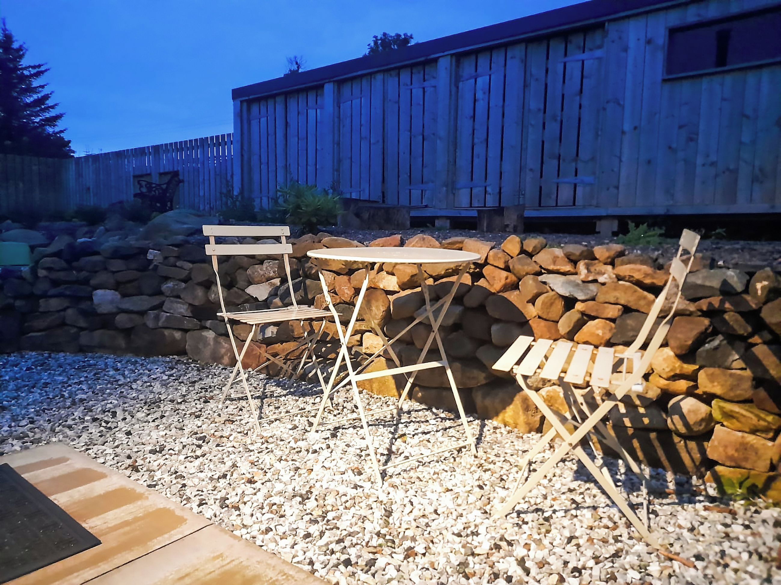 Un espace extérieur aménagé avec des sièges, un mur en pierre et des meubles en bois.