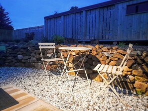 An outdoor seating area with a stone wall and wooden furniture. - 2 bedroom accommodation in Torrin, Isle of Skye (Torrin, Isle of Skye)
