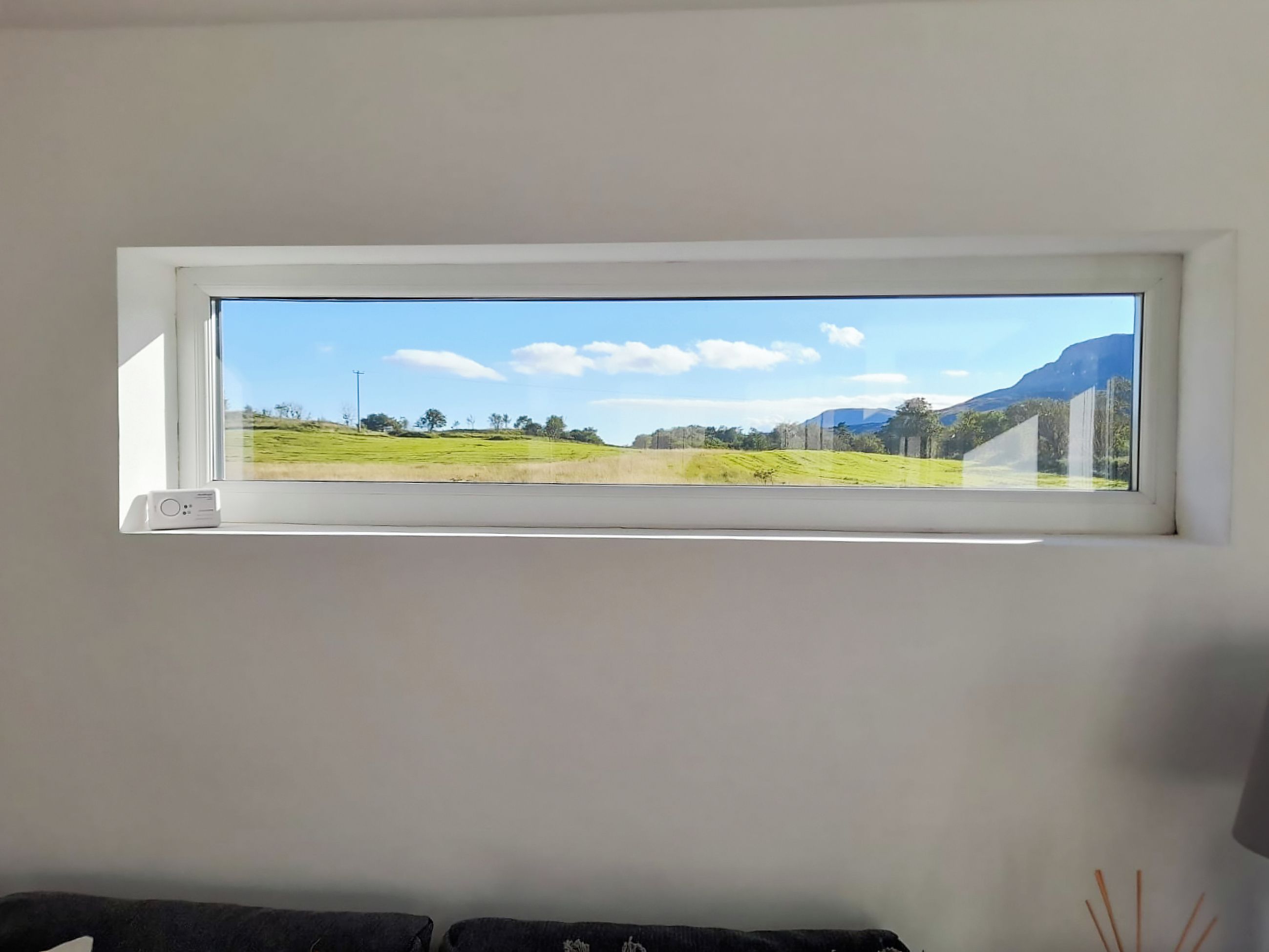 Una habitación con un amplio ventanal que da a un paisaje verde y montañas.