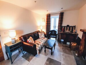 A living room with a sofa, a coffee table, a side table, a chair, and a fireplace with a mantel.