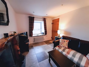 Una sala de estar con sofá, mesa de centro, televisor, chimenea y ventana con cortinas.