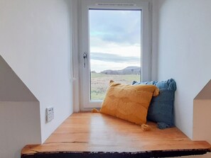 A corner room with a window, a wooden bench, and two pillows. - 2 bedroom accommodation in Torrin, Isle of Skye (Torrin, Isle of Skye)