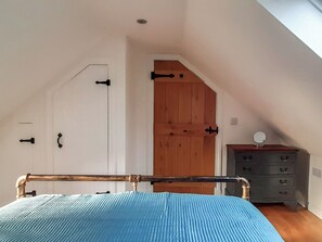 A bedroom with a bed, a dresser, a door, and a wooden panel wall. - 2 bedroom accommodation in Torrin, Isle of Skye (Torrin, Isle of Skye)