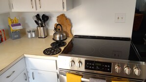 Une cuisine équipée d’une cuisinière, d’un four et de divers ustensiles.