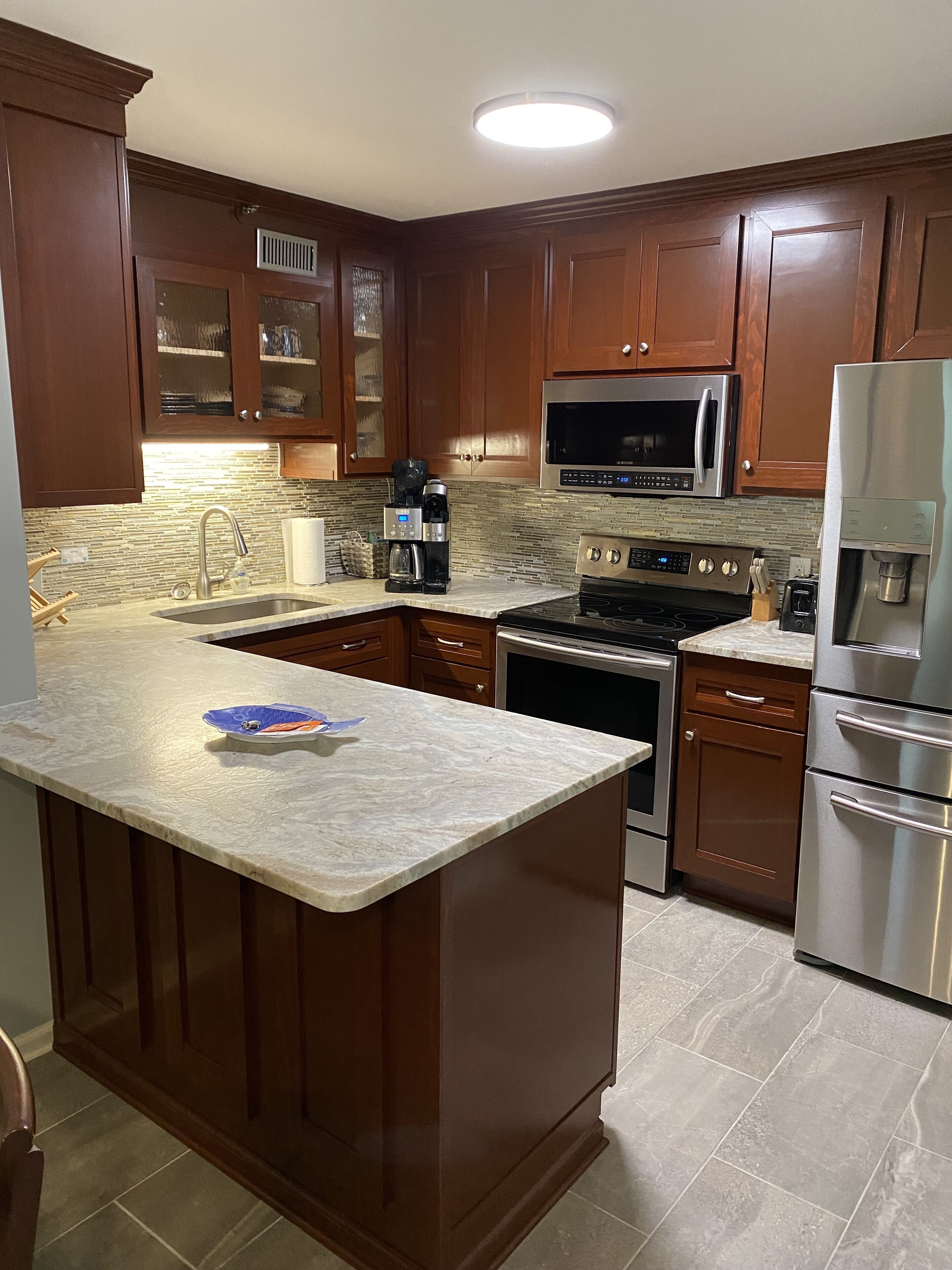 A kitchen with wooden cabinets, a stainless steel refrigerator, a microwave, an oven, and a coffee maker.