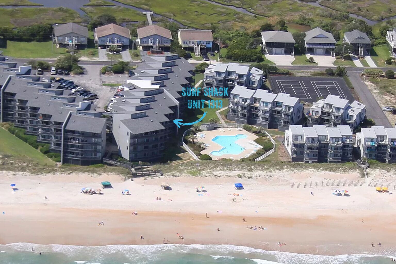 A resort with multiple buildings, a swimming pool, and a beach.