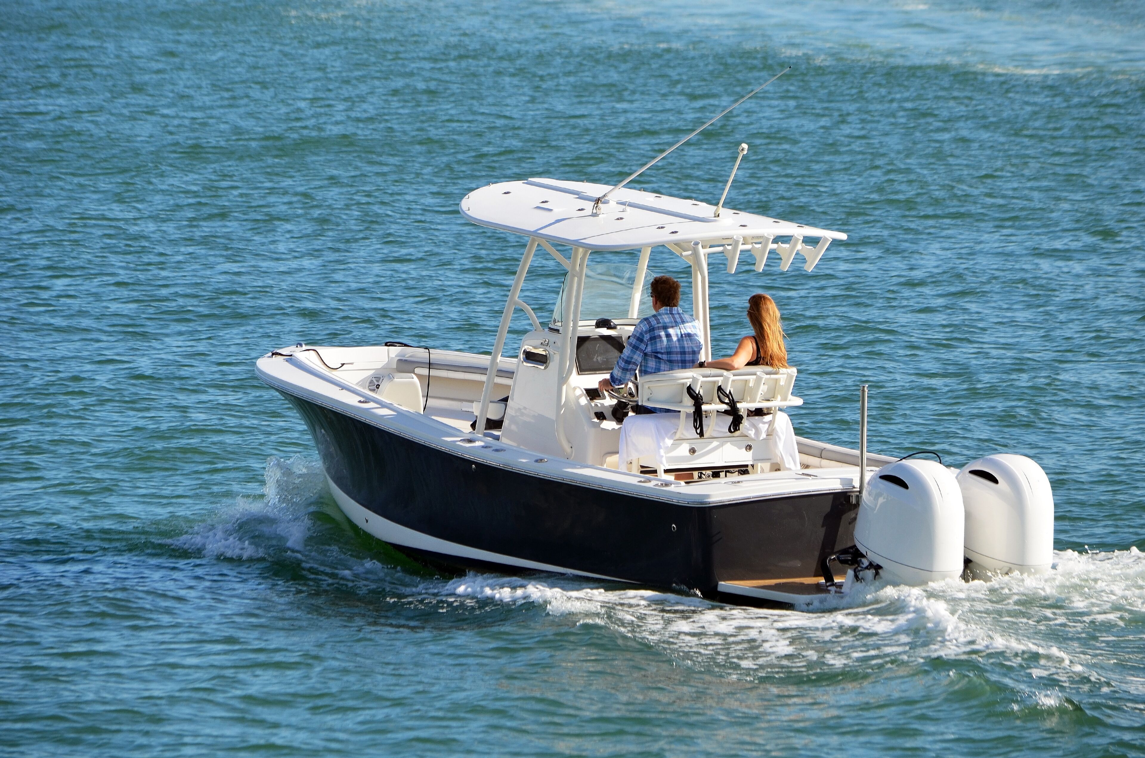 A small motorboat with two people on board, moving through calm water.
