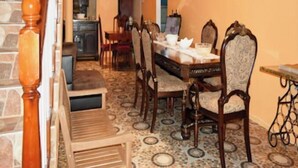 Een eetruimte met een houten tafel en stoelen, een kroonluchter en een trap met een houten leuning.