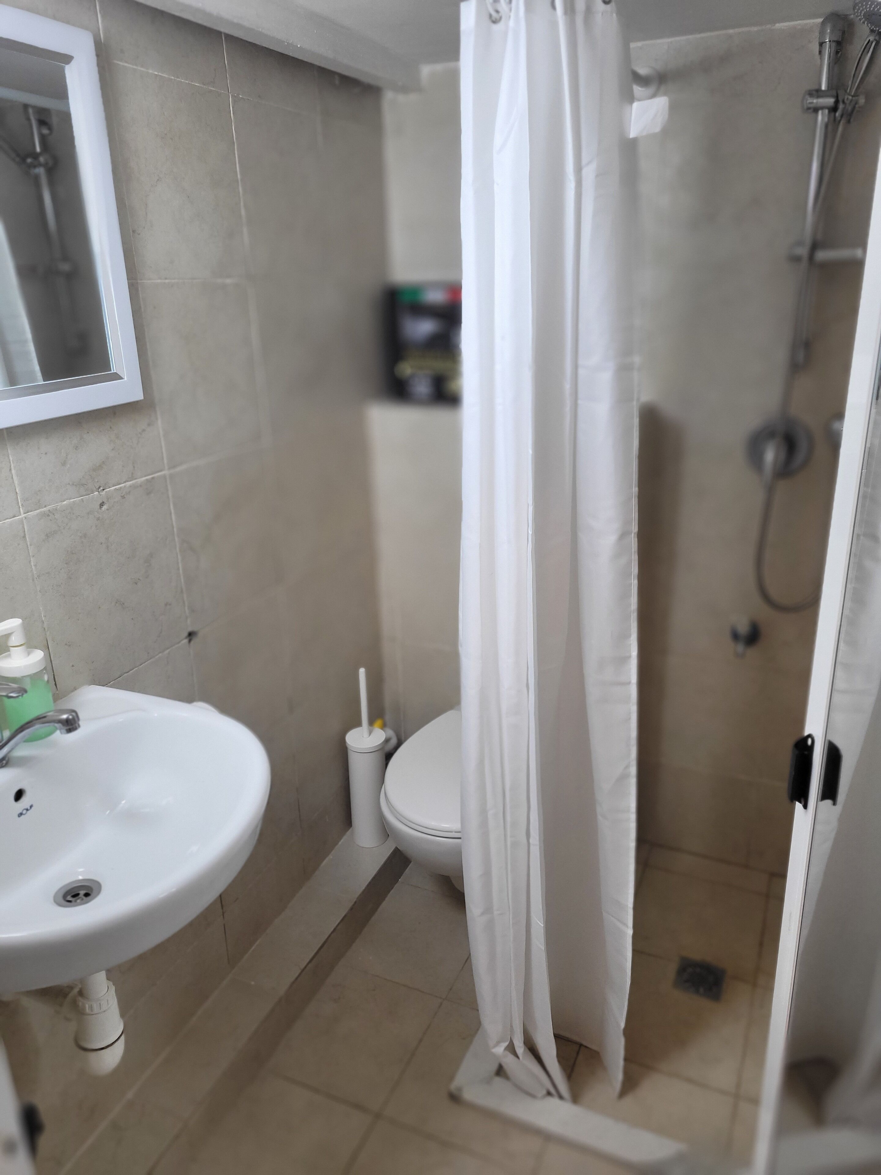 A bathroom with a white sink, toilet, and shower.