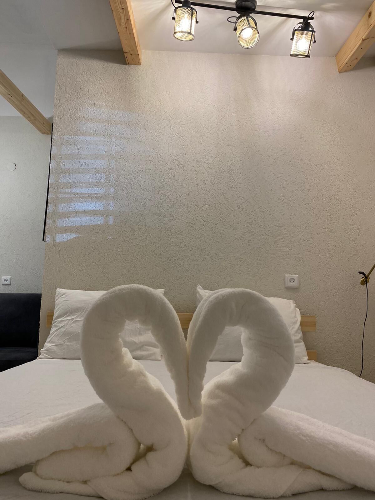 A hotel room with a bed, a headboard, and a wall-mounted light fixture.