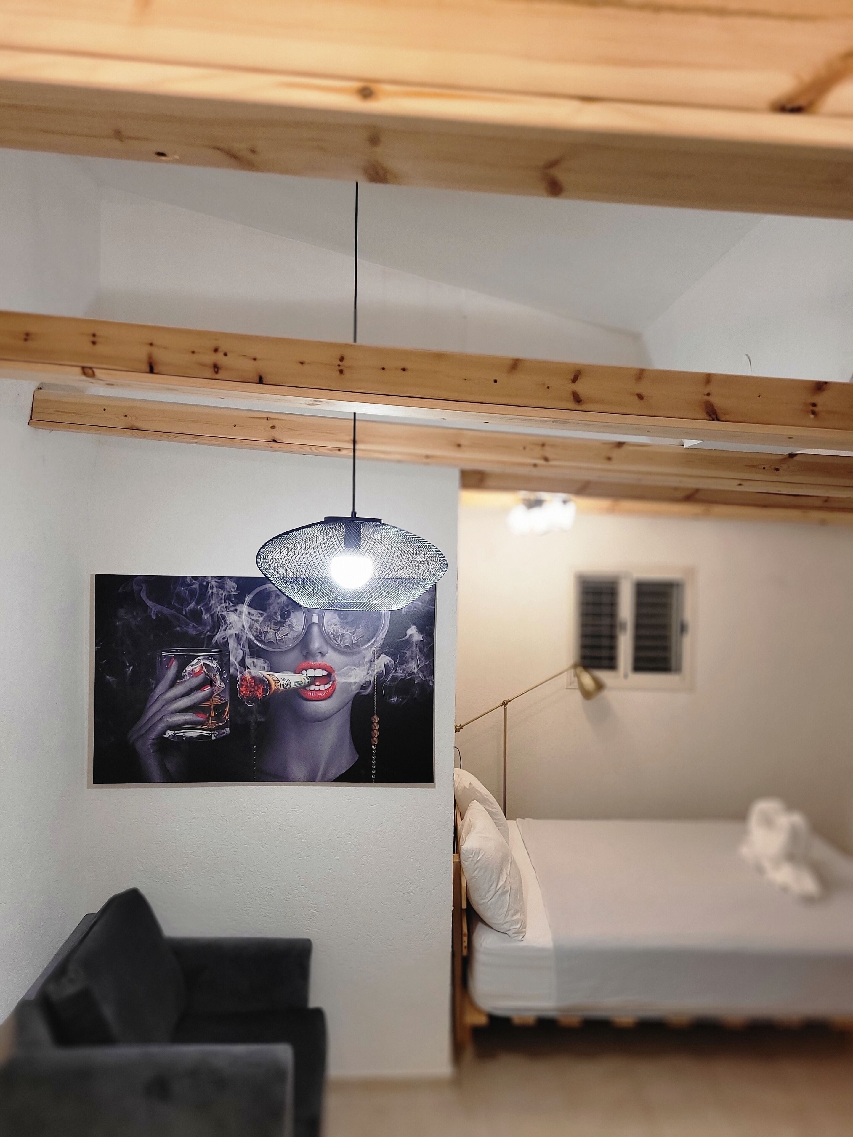 Een kamer met een bed, een hanglamp en een poster aan de muur.