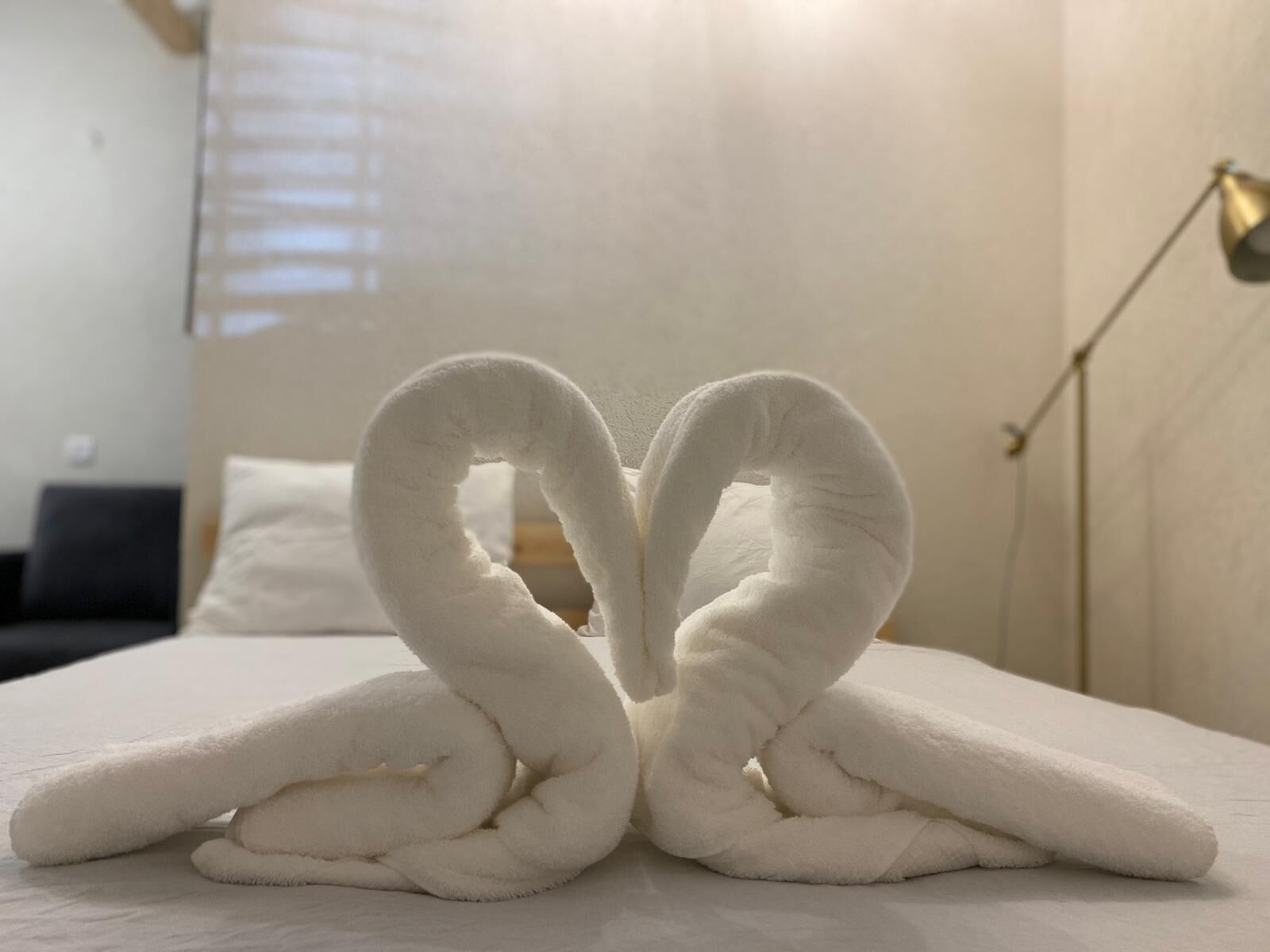 Una cama con una toalla dispuesta en forma de corazón.