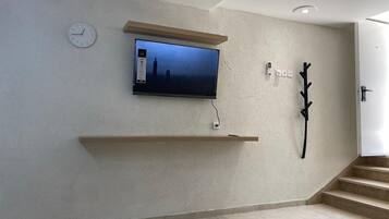 A modern interior with a mounted TV, a clock, and a coat rack.