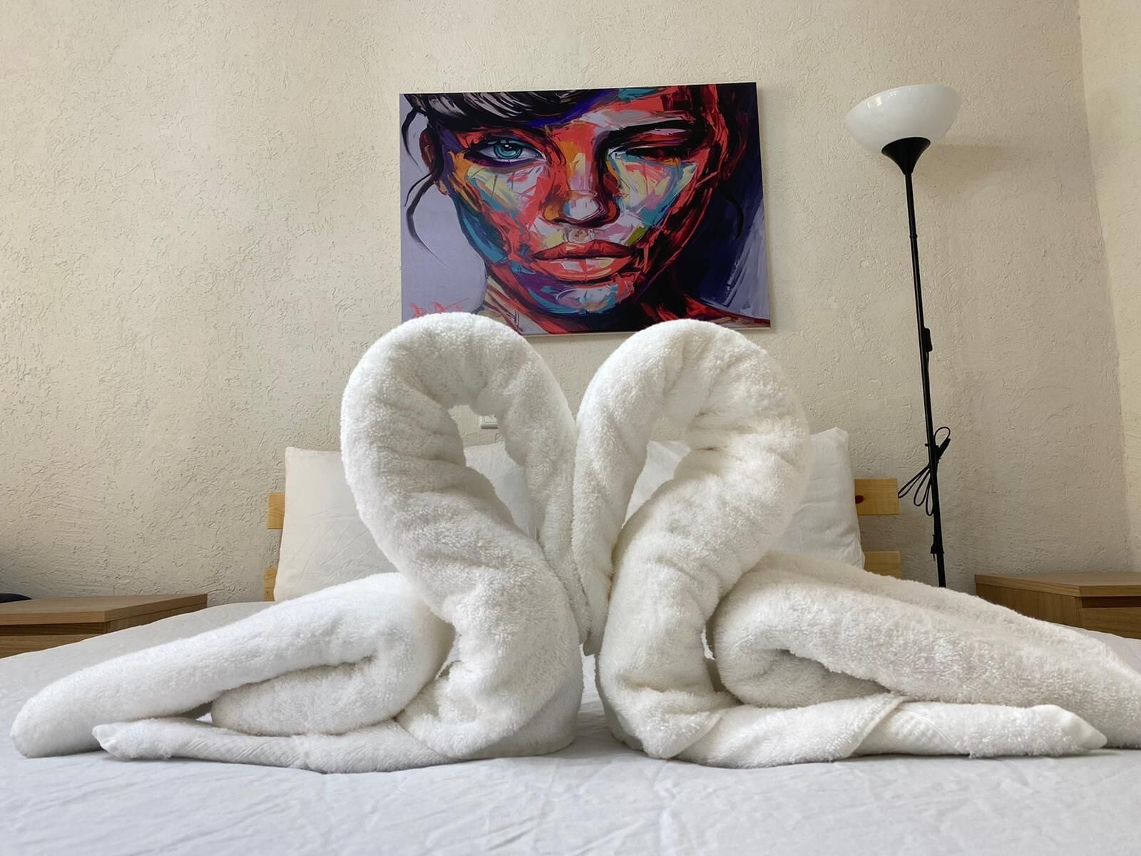 A bed with white pillows and a white blanket folded in the middle.