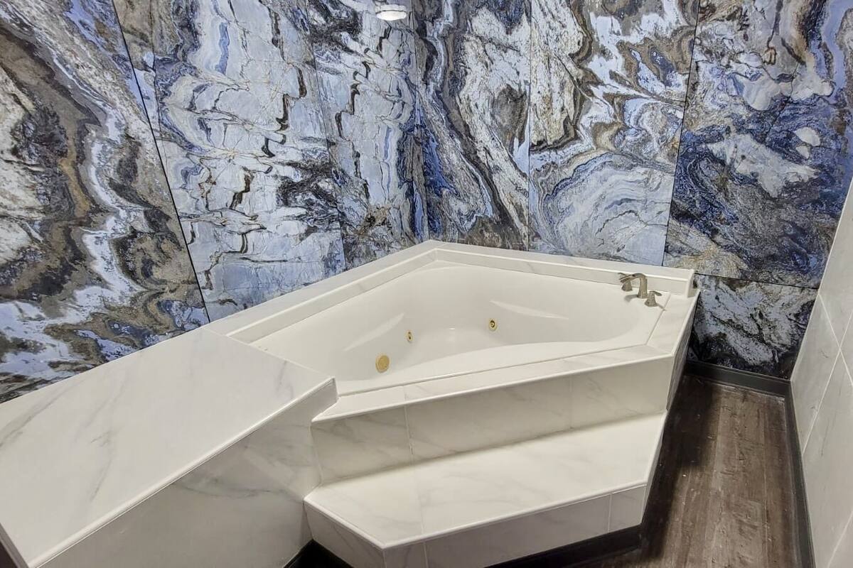 Un baño moderno con una bañera independiente, paredes de mármol y suelo de baldosas.