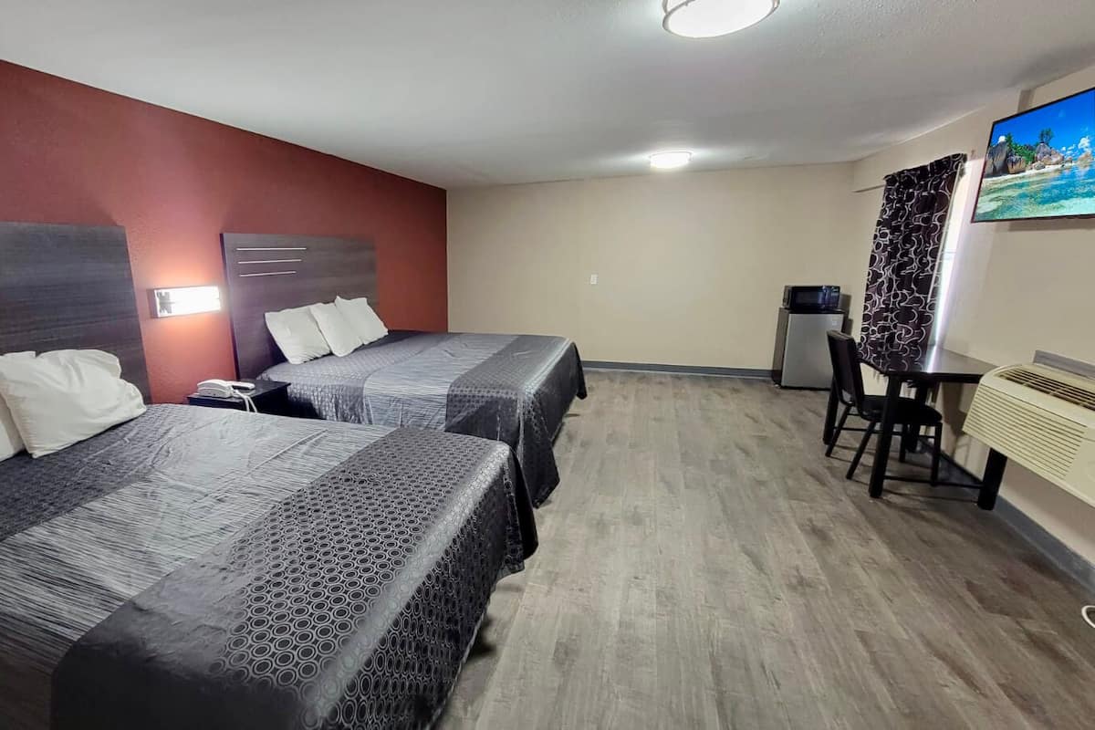 Habitación de hotel con dos camas, un escritorio y una silla.