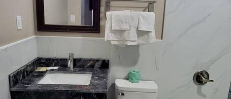 Un baño con lavamanos de mármol, inodoro, bañera y espejo.