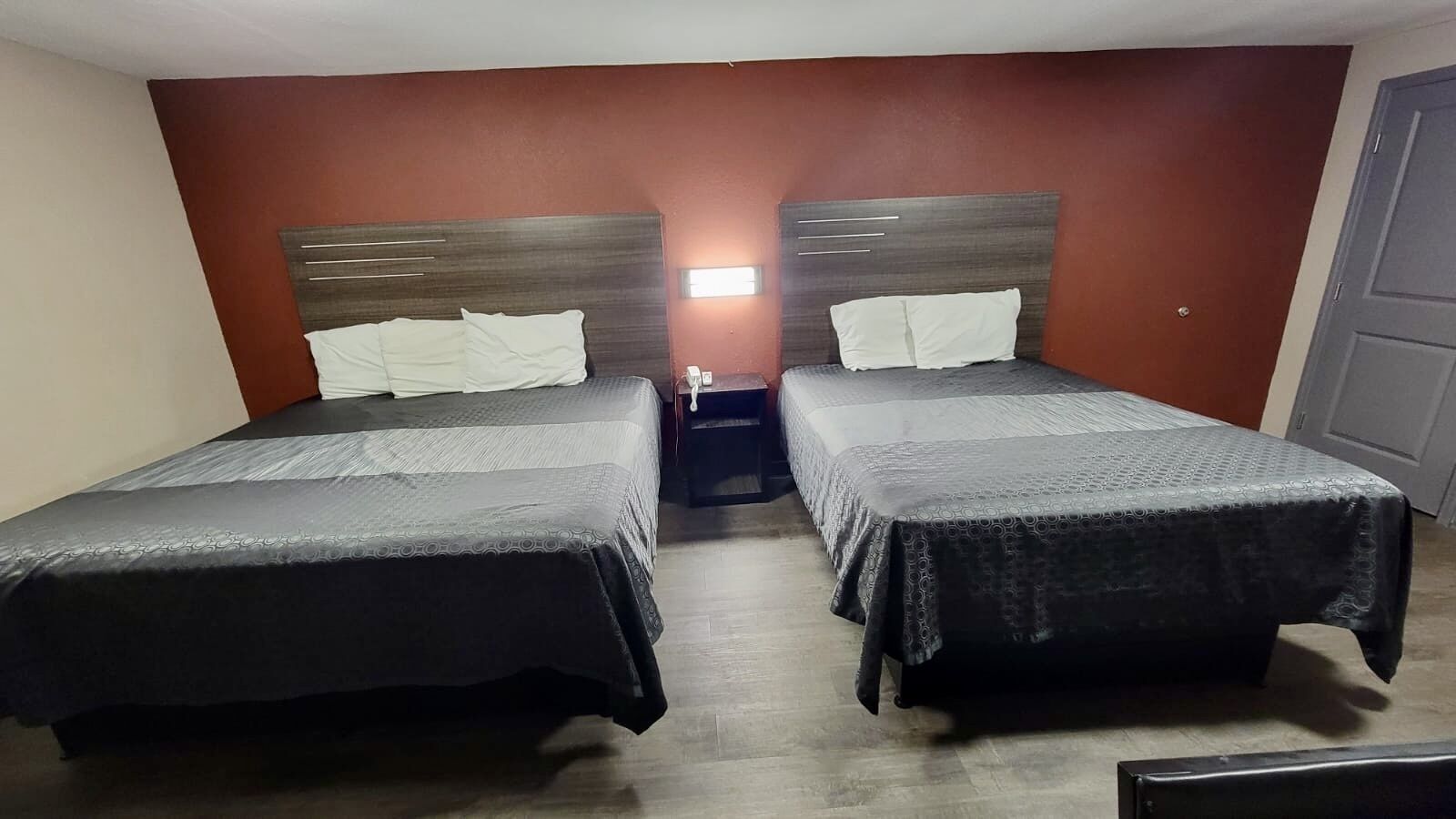 A room with two beds, each with a headboard and a bedside table.