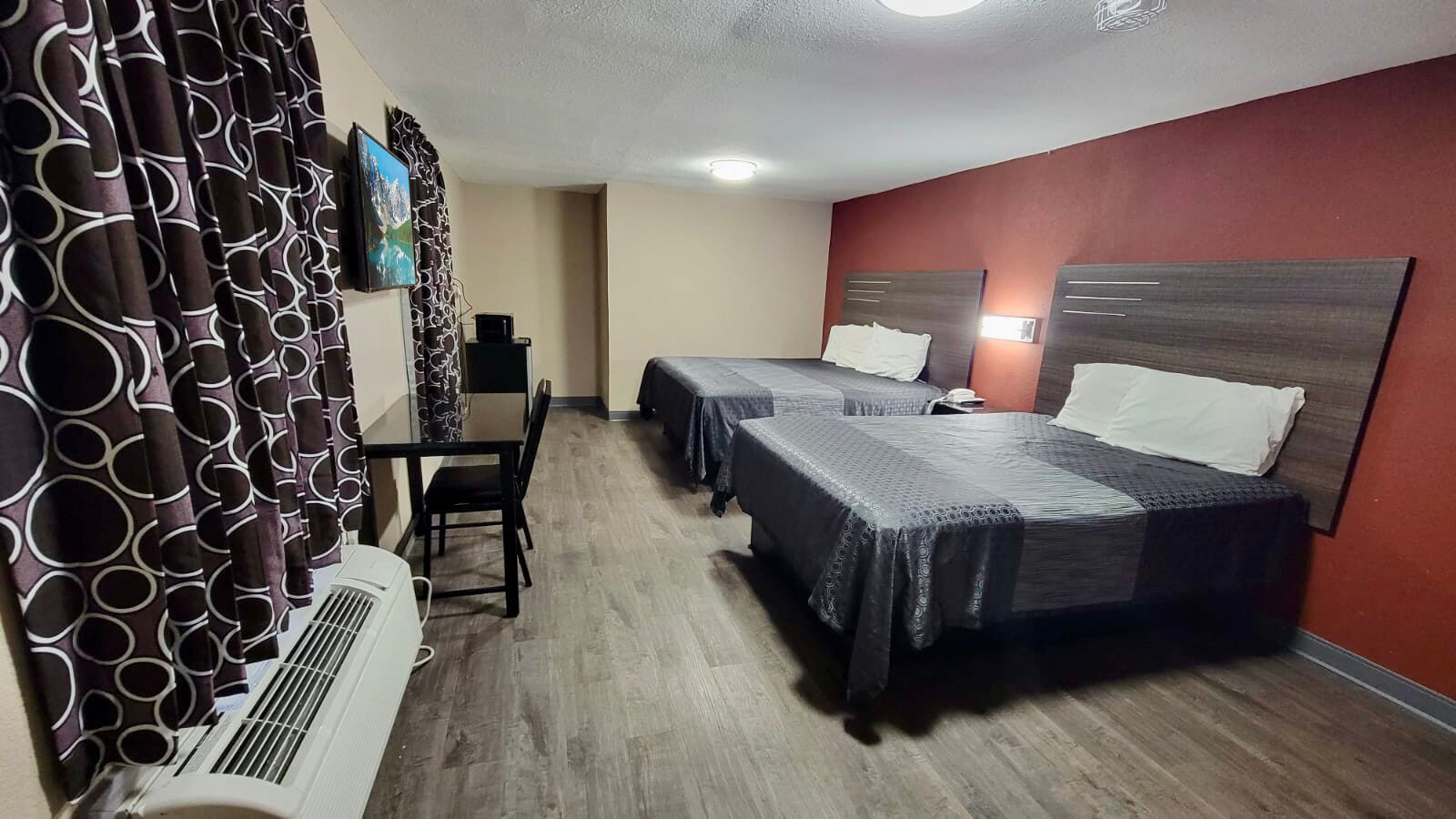 Ein Hotelzimmer mit zwei Betten, einem Schreibtisch und einem Stuhl.