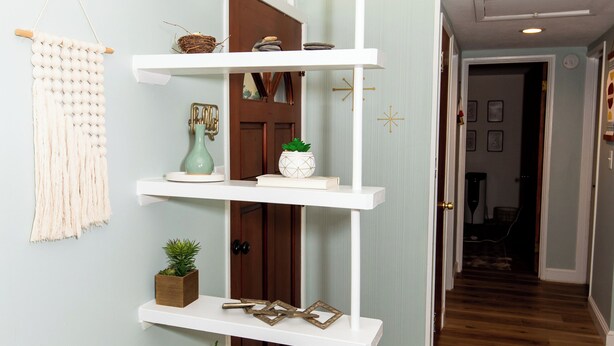 A hallway with a white shelving unit against a light blue wall, wooden flooring, and a door with a decorative handle. - Mid-Century Modern Themed Surf House (Vermilion)