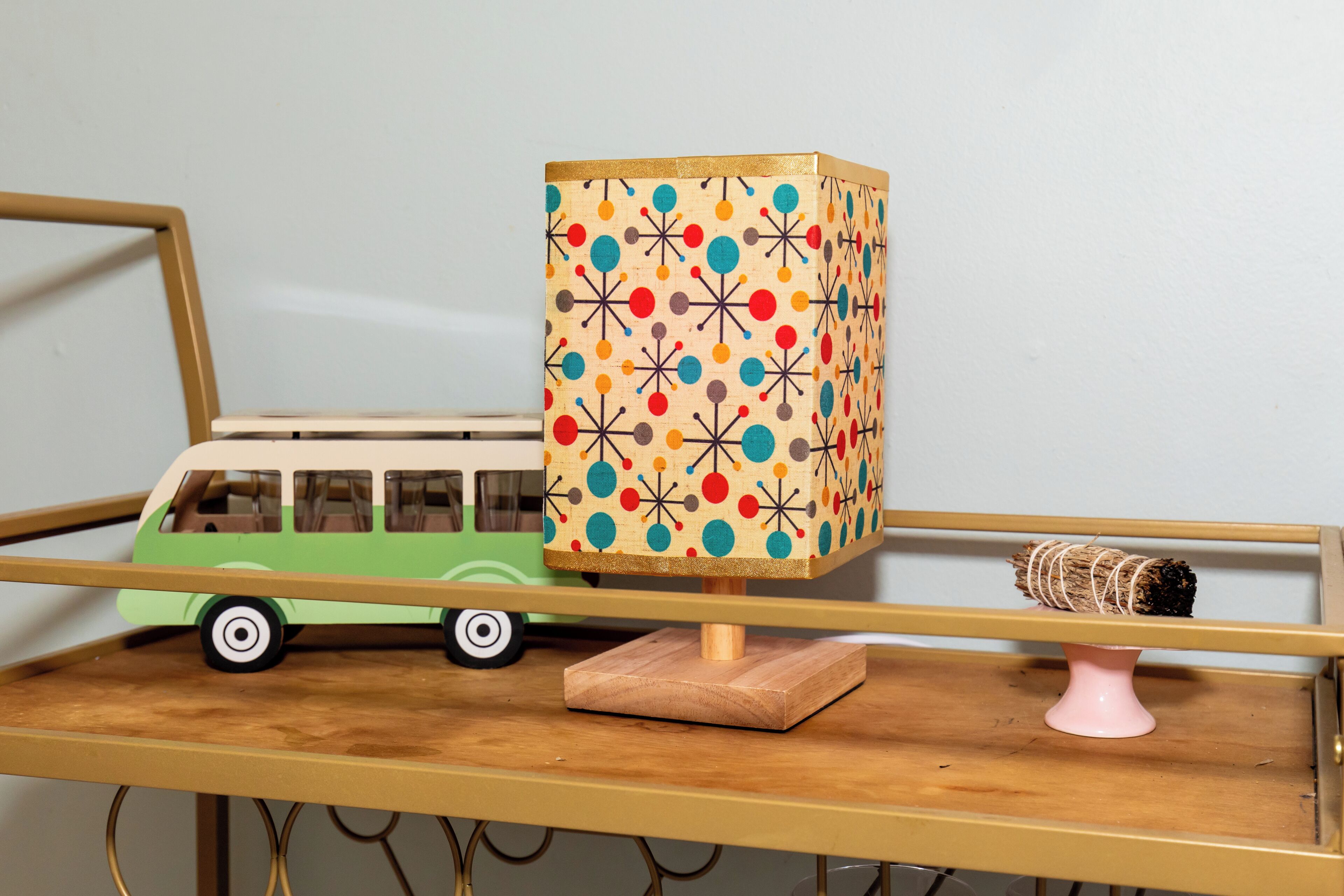 Une étagère en bois avec un autobus jouet et une lampe.