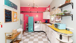 A kitchen with a checkered floor, a teal refrigerator, a microwave, and a sink. - Mid-Century Modern Themed Surf House (Vermilion)