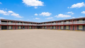 A multi-story motel with a central courtyard, featuring balconies and a clear sky.