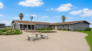 A motel with a covered patio, outdoor seating, and a sign indicating the name.