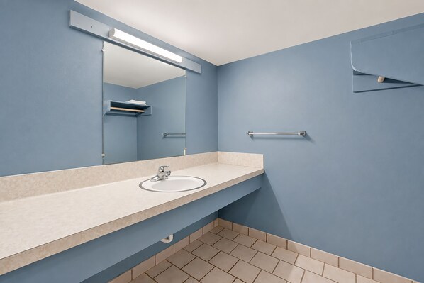 A bathroom with a sink, mirror, towel rack, and tiled floor.
