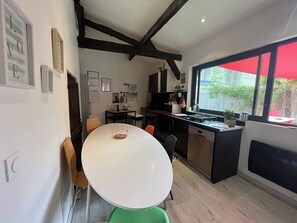 Una cocina moderna con una mesa blanca, gabinetes negros y un ventanal con un paraguas rojo.