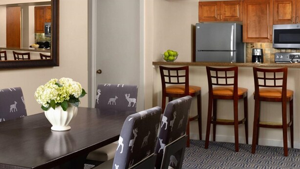 Un comedor con una mesa de madera oscura, cuatro sillas con tapicería estampada y un jarrón con flores.