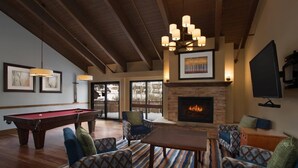 Una sala de estar acogedora con mesa de billar, asientos cómodos, chimenea y televisor.