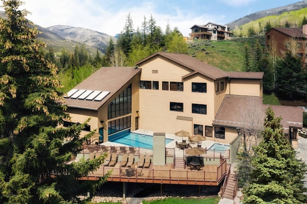 A two-story building with a swimming pool, outdoor seating, and a deck.