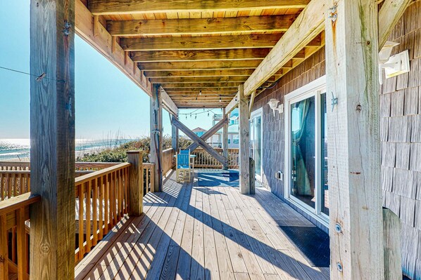 Enjoy the serene views of the water from this expansive deck, featuring a glass door leading to the interior and a wooden railing.