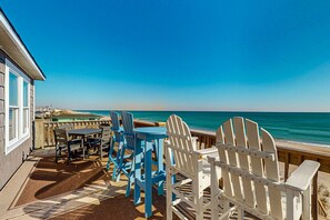Enjoy meals with a view from this seaside patio, featuring Adirondack chairs and a dining table.