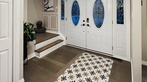 Un pasillo con alfombra estampada, una escalera y un par de puertas con paneles de vidrio.
