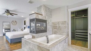 A modern bathroom with a marble sink, a large bathtub, and a ceiling fan. - Grovenor. Sleeps 14. Family Home. Triple Garage. (Edmonton)