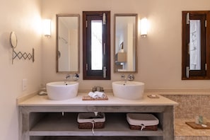Un baño con dos lavamanos, espejos y un revestimiento de piedra en la pared.