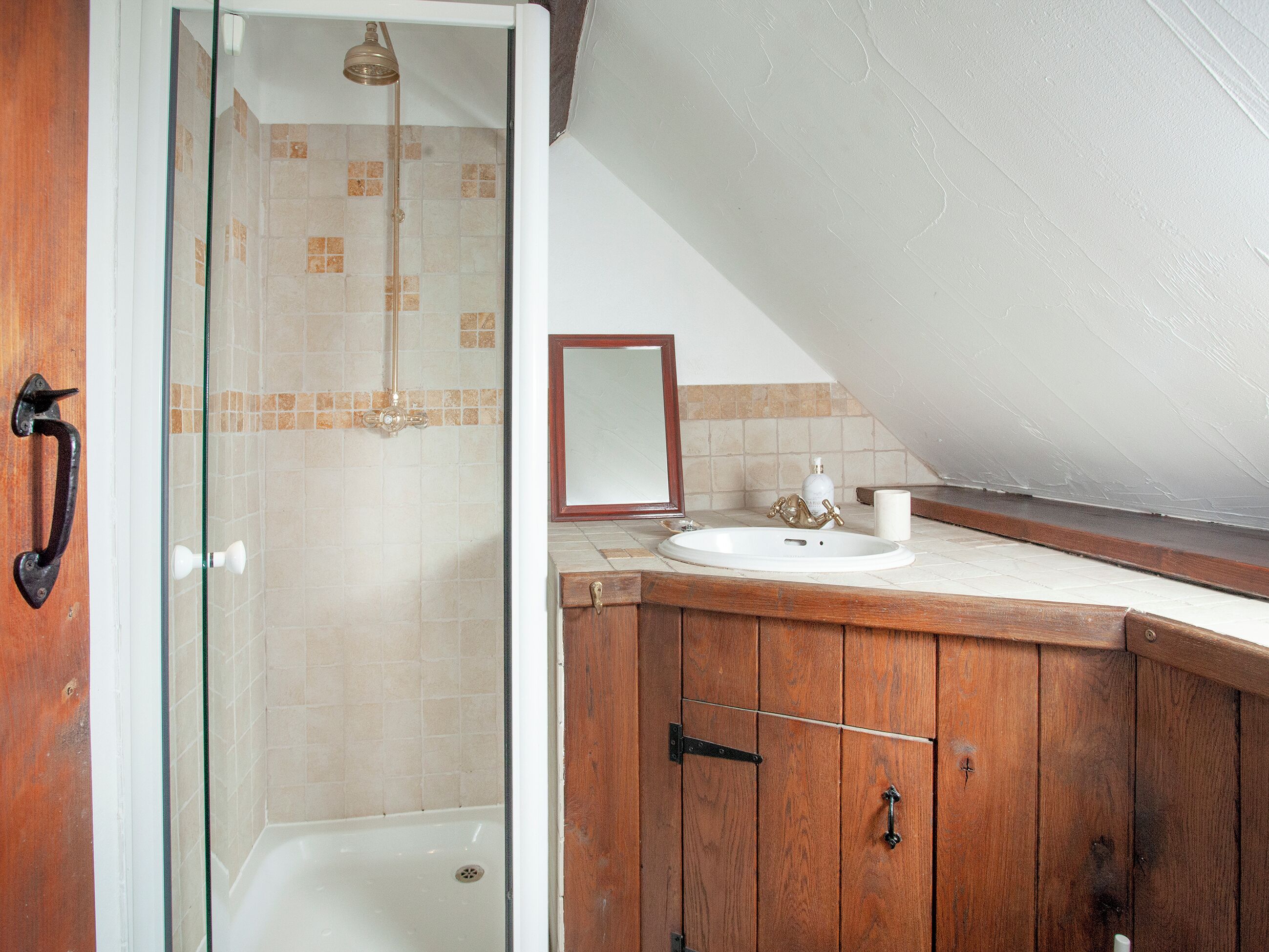 Une salle de bain dotée d’une douche à parois de verre, d’un meuble-lavabo en bois, d’un lavabo et d’un miroir.