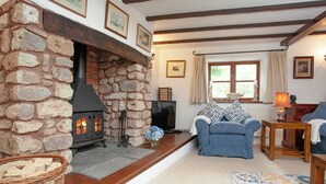 Un salón acogedor con chimenea de piedra, un sofá azul y una mesa de madera.