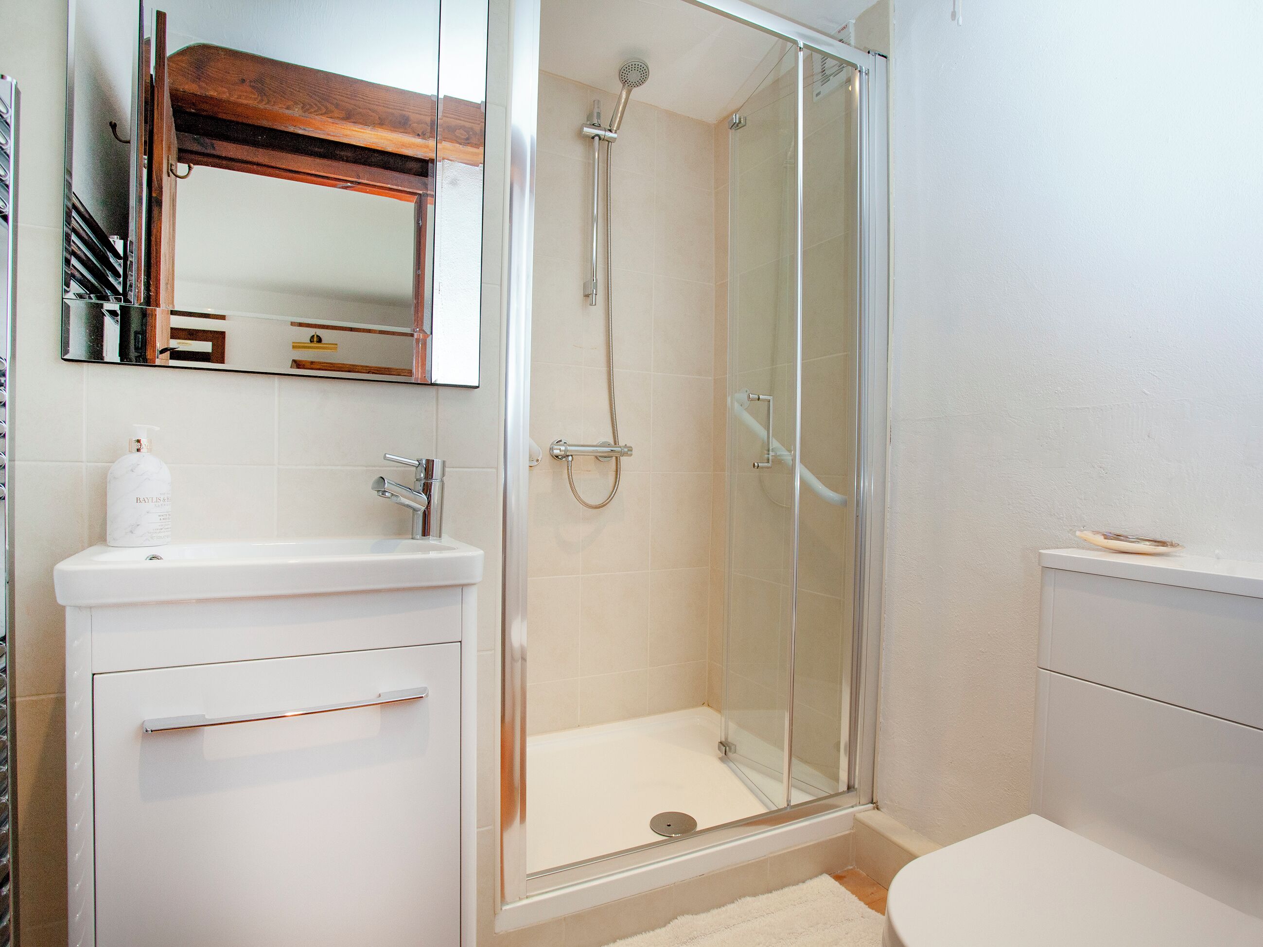 A bathroom with a glass-enclosed shower, a white sink, and a mirror above the sink.